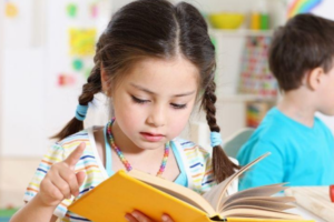 Alt text: Young girl reading book in classroom