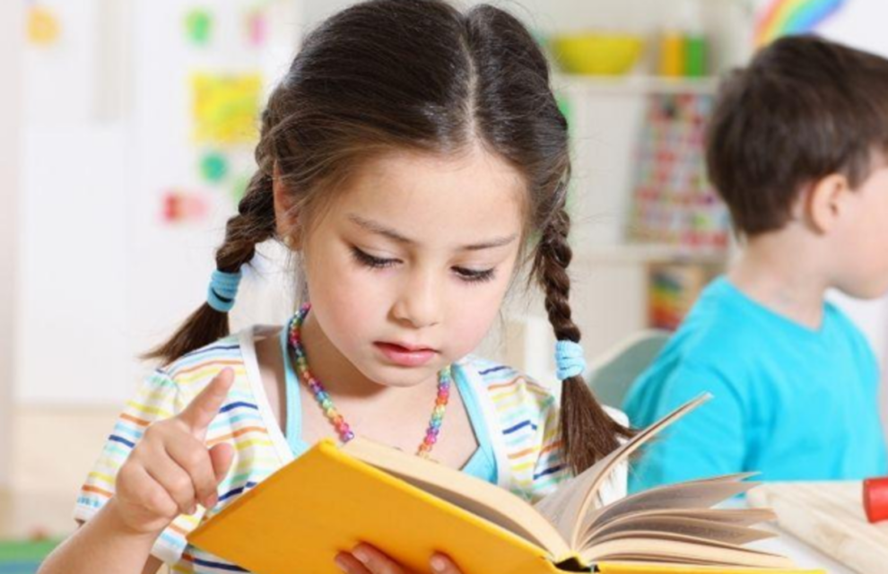 Alt text: Young girl reading book in classroom